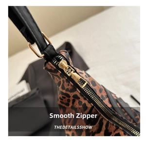 Detail of leopard print shoulder bag with smooth golden metal zipper and black leather strap