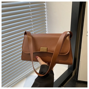 Detail view of caramel brown leather handbag with a textured golden metal lock buckle