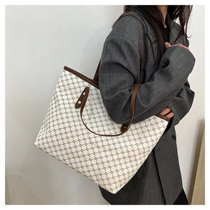 Detail of canvas tote bag featuring brown Triomphe pattern and premium leather straps