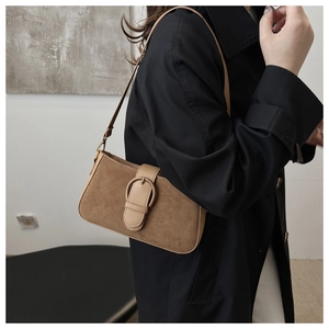 Detail of a brown suede rectangular shoulder bag with vintage gold buckle on a model