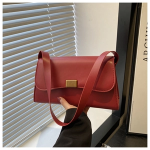 Close-up of vintage deep red leather handbag with golden rectangular metal buckle