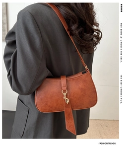 Detailed view of caramel brown leather texture and golden metal hook on the baguette bag