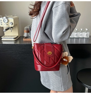 Détail du sac seau rouge matelassé avec fermoir doré et pendentif monstre en peluche