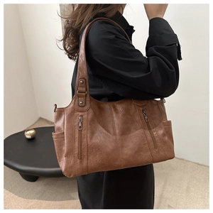 Detail showing the retro brown leather tote bag with vertical zippers and wide shoulder strap
