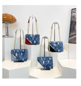 Dettaglio di quattro borse patchwork in denim con catene dorate su basi bianche