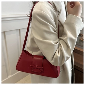 Detail der roten Leder-Baguette-Tasche mit Schleifendekoration am weißen Blazer-Outfit