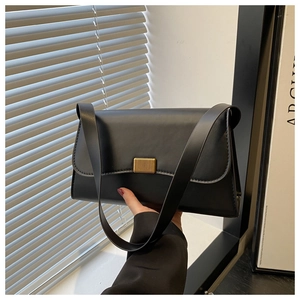 Close-up of black leather underarm bag featuring a stylish gold striped metal buckle