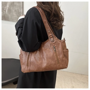 Rear view of a model wearing a large brown retro tote bag with zipper pocket detail