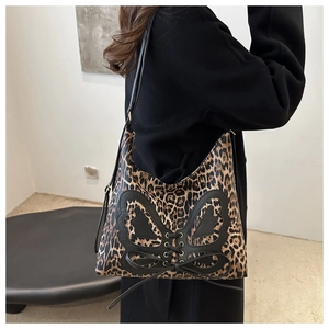 Detail of leopard print tote bag with butterfly tie design worn with a black coat