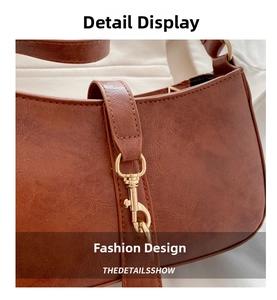 Detail of caramel brown faux leather baguette bag with golden hook and fine stitching