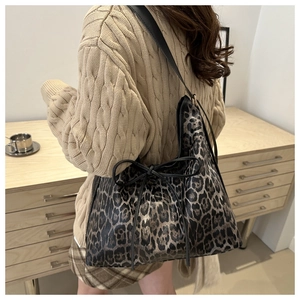 Détail d'un sac cabas léopard avec nœud en cuir noir sur un modèle à l'épaule