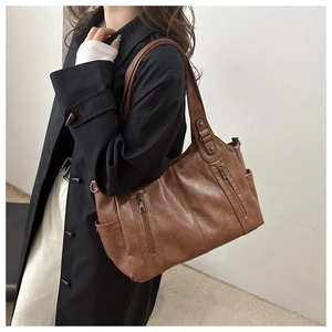 Close-up of a vintage brown tote bag with textured faux leather and vertical zipper pockets