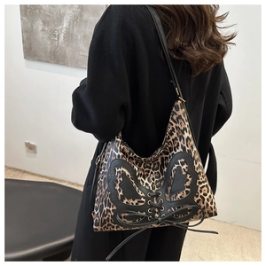 Detail of leopard print crossbody bag with black leather butterfly and lacing decoration