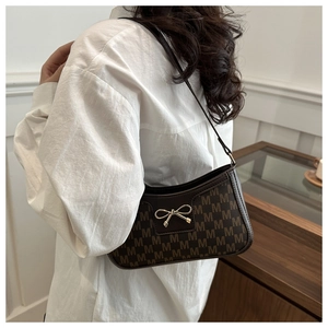 Detailed close-up of brown bow buckle and M-pattern on stylish shoulder bag