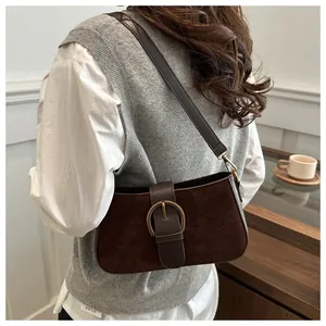 Detail of dark brown suede shoulder bag featuring a vintage golden horseshoe buckle