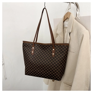 Detail view of large check pattern tote bag with vintage leather handle and metal rivets