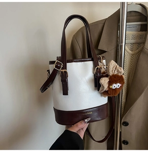 Détail du sac seau bicolore avec touches de cuir marron et pendentif chouette en peluche