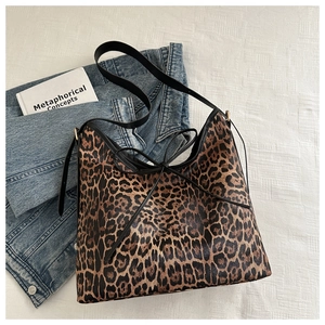 Detail of leopard print tote bag with black leather straps and elegant bow ties