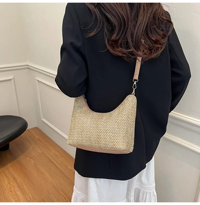 Detail of woven straw shoulder bag with light brown strap on a model for a minimal look