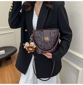 Détail d'un sac seau matelassé marron foncé avec fermoir doré et charme ange en peluche
