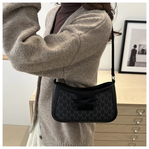 Detail of black monogram shoulder bag with leather bow and retro moon shape design