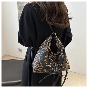 Close-up of leopard print shoulder bag with black bow and lace-up details on model