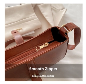 Detail of smooth gold zipper and high-quality leather texture on brown shoulder bag