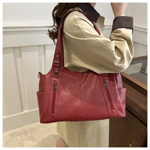 Side view of large red vintage tote bag with dual zipper pockets on a female model