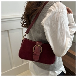 Detail of burgundy leather and suede stitching underarm bag with gold circular buckle