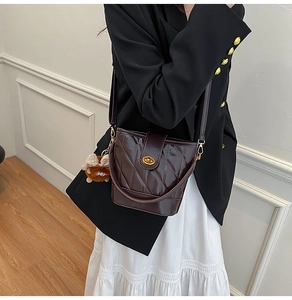 Close-up of quilted bucket bag with gold twist lock and plush bear charm detail