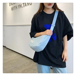 Détail du sac croissant bleu clair en nylon avec bandoulière réglable porté par le modèle