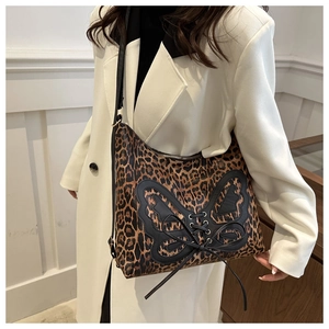 Detail of leopard print tote bag with black leather butterfly appliqué and straps