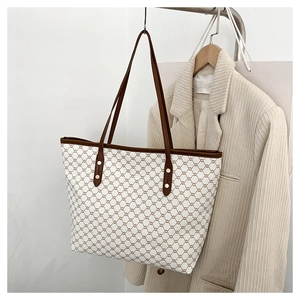 Close-up of geometric pattern tote bag with leather straps and golden rivet details