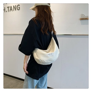 Détail du sac demi-lune blanc en nylon avec étiquette Feiyue porté en bandoulière