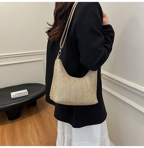 Close-up of woven straw crescent tote bag with leather strap on stylish model