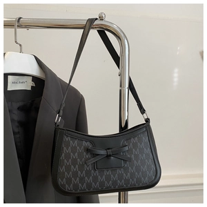 Detail of black underarm bag featuring M-pattern monogram and 3D bow decoration