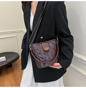 Détail d'un sac seau matelassé marron foncé avec fermoir rotatif doré élégant