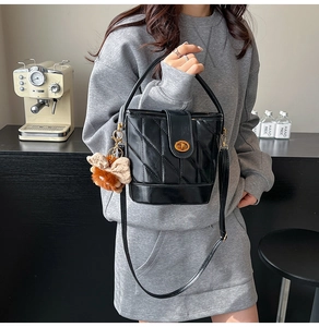 Détail du sac seau noir matelassé avec fermoir doré et pendentif noeud en peluche