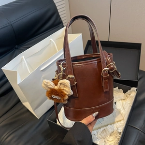 Sac seau marron foncé avec charm nœud en peluche et texte embossé à la mode
