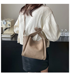 Detail of khaki lychee textured bucket bag with decorative knot handle and fashion logo