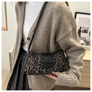 Nahaufnahme der Leoparden-Halbmondtasche mit schwarzer Lederschleife am Model