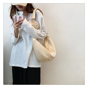 Détail du sac bandoulière beige en forme de croissant avec petit porte-monnaie assorti