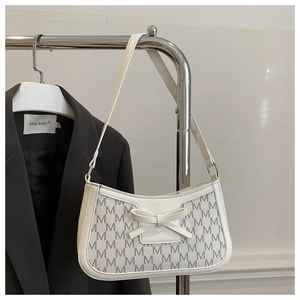 Close-up of white shoulder bag featuring grey M-pattern print and a bow detail