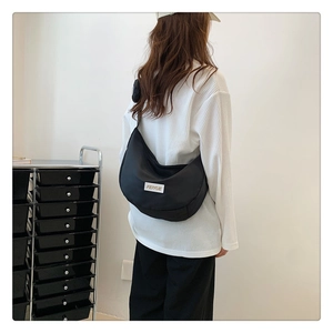 Détail du sac croissant en nylon noir avec le logo Feiyue tissé blanc sur le devant