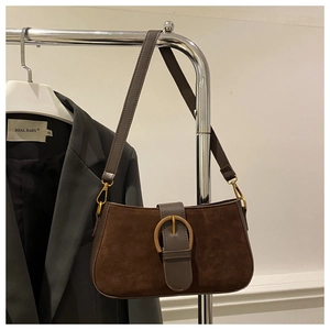 Détail du sac bandoulière en daim marron foncé avec boucle fer à cheval dorée chic