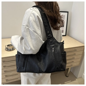 Detailed side view of black vintage tote bag with pebbled leather texture and multi-pockets