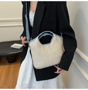 Detail of a woven straw tote bag with light blue leather straps and crossbody styling