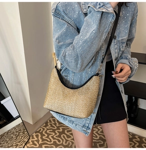 Detail of woven straw hobo bag with black leather strap worn by a model in casual style