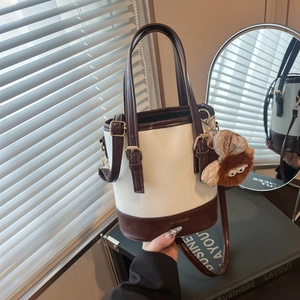 Sac seau chic bicolore en cuir avec pendentif en peluche et boucles dorées élégantes