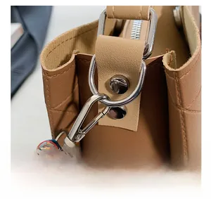 Detailed close-up of silver metal hardware and colorful woven strap on a brown tote bag